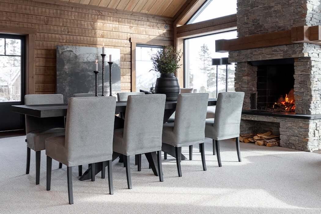Esstisch mit grauen Polsterstühlen in gemütlichem Raum mit Kamin