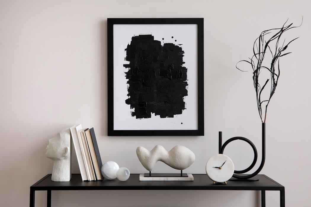 Dekoriertes Sideboard in schwarz-weiß mit Bild, Vase, Büchern und Skulpturen im modernen Stil