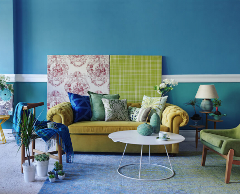 Fehlkäufe beim Möbelkauf vermeiden: Sofa mit verschiedenen Materialien und Farbmustern an der Wand und verschiedenen Kissen und Sesseln zur Auswahl