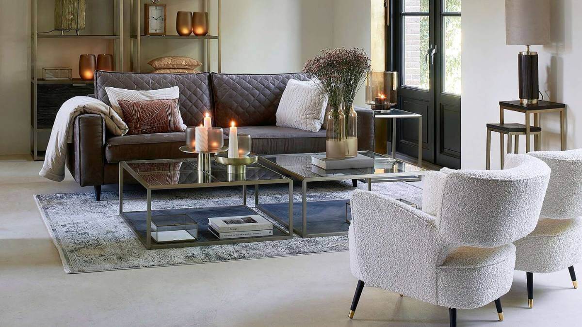 Moderner Landhausstil von Riviera Maison in einem Wohnzimmer mit Ledercouch und zwei Boucle-Sesseln