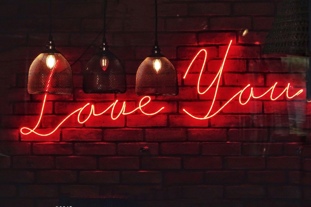Love you in roter Neon-Schrift auf Ziegelwand - ein Spruch der Liebe