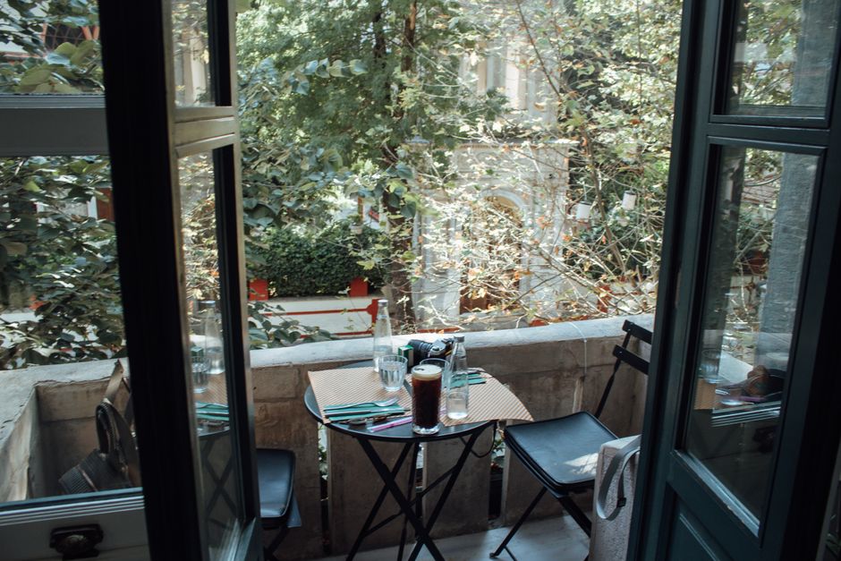 Cozy small balcony with a round bistro table, two metal chairs and several potted plants, showcasing balkon möbel